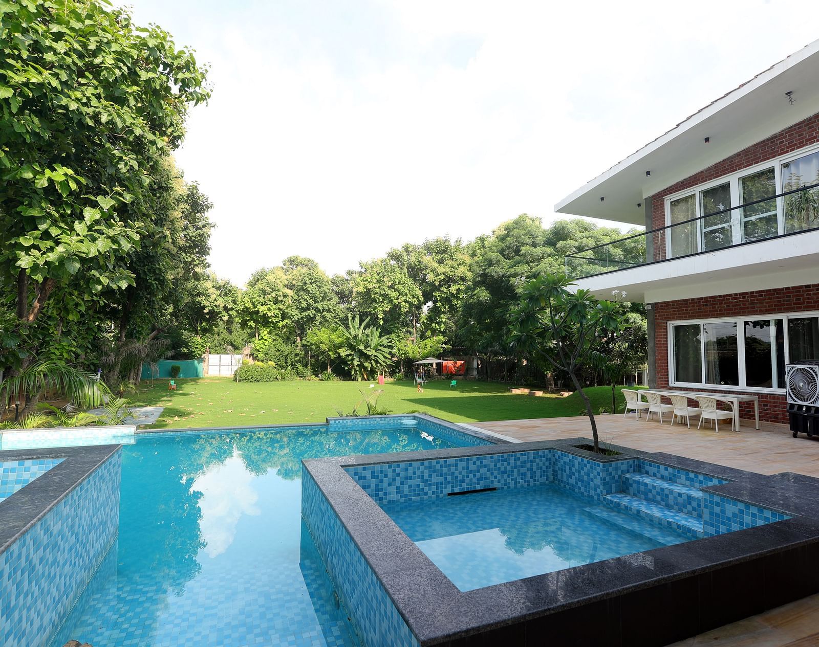A  farmhouse with a sparkling swimming pool, surrounded by lush garden at Tisya Farms, Gurgaon.
