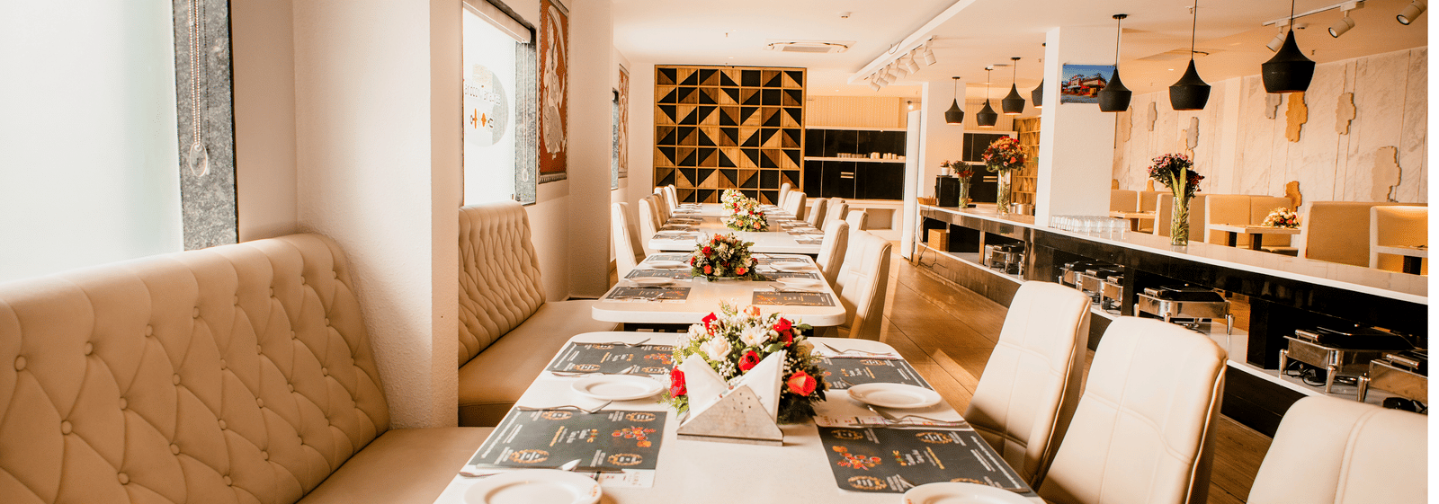 Set tables with plates, menus and floral centrepieces beside tufted booths and buffet counters at Tandoori Tamashaa, Ilara Hotels & Spa, Tada.