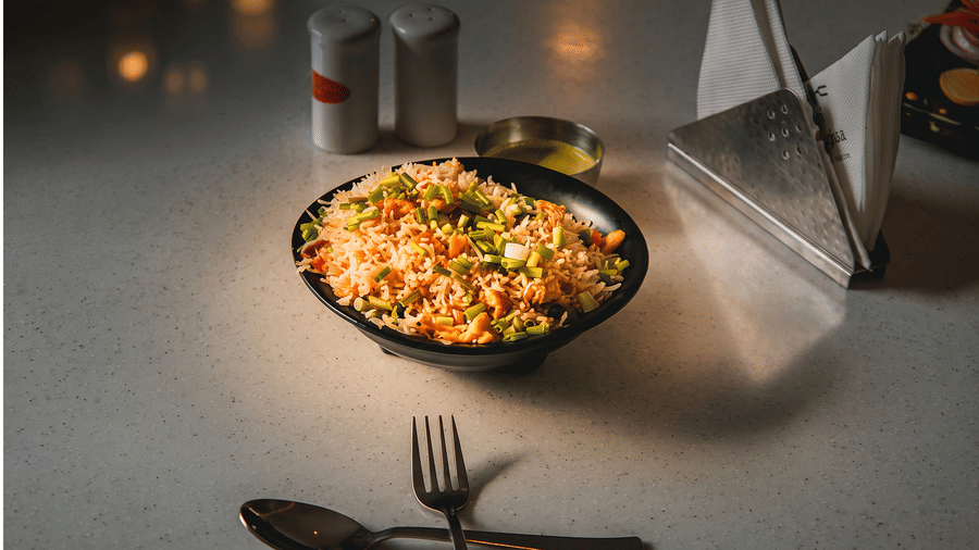 Bowl of fried rice topped with spring onions, served with green chutney and salt and pepper shakers at Tandoori Tamashaa, Ilara Hotels & Spa, Tada.