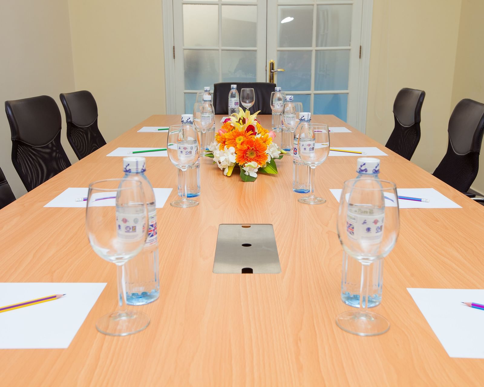 A meeting room with a long table, chairs, and glasses | Conference Hall | Central Mansions, Phnom Penh