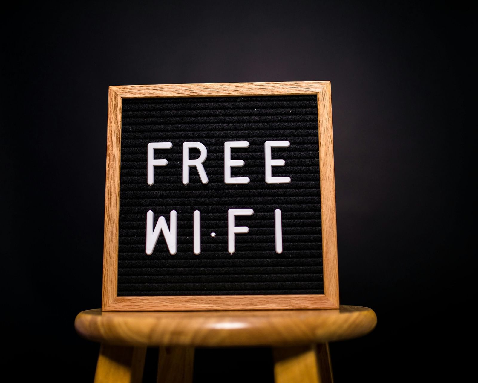 A wooden framed sign displaying 'Free Wi-Fi' in white letters on a black background, sitting on a wooden stool.