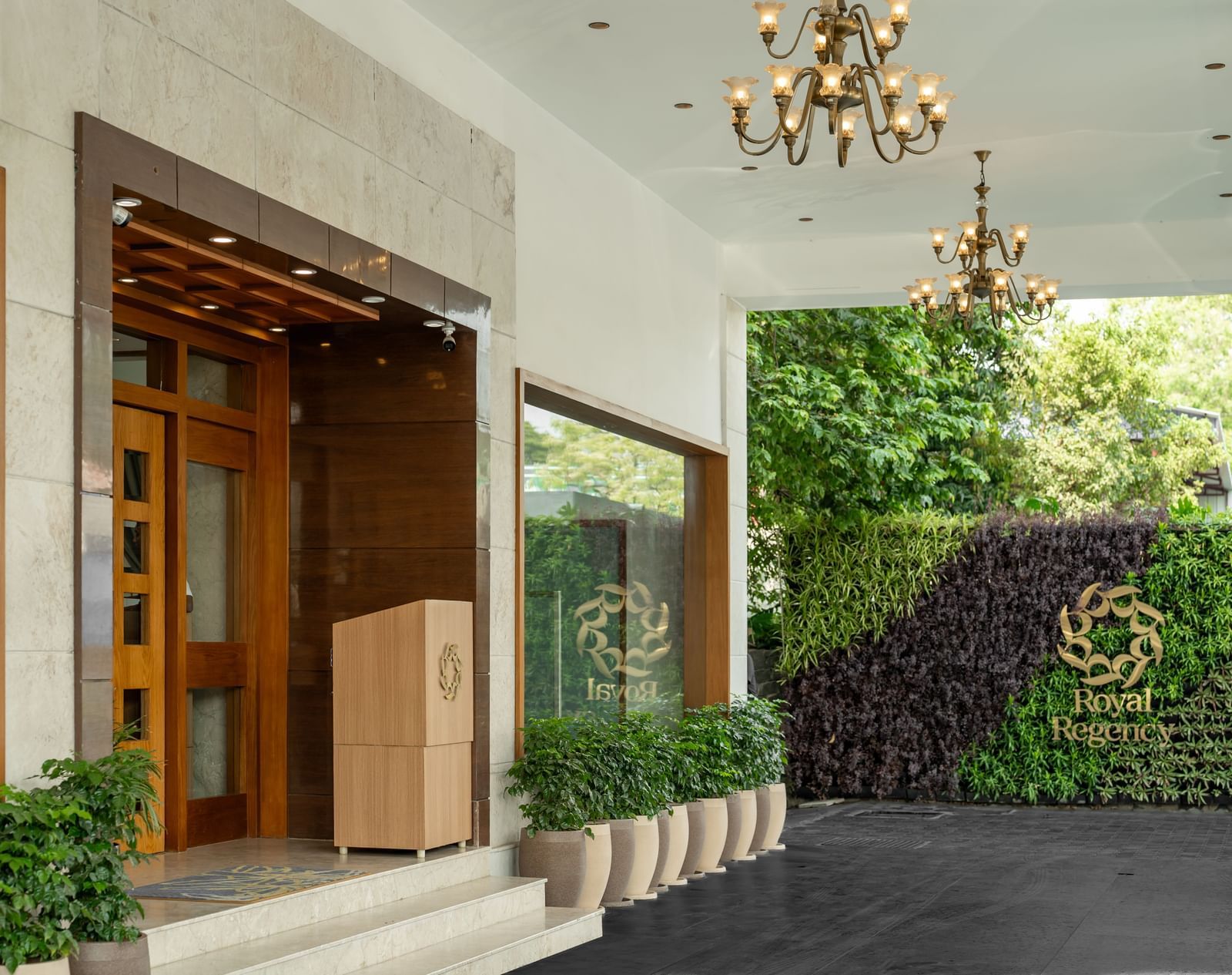 Hotel Royal Regency Chennai entrance with glass doors, greenery, and chandelier