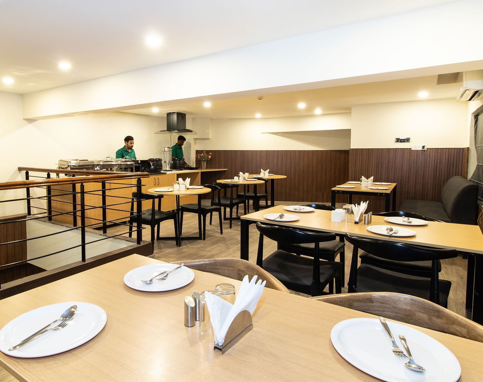 A dining area with wooden tables and chairs in a warm inviting setting - Sanctum Suites Richmond Road, Bangalore