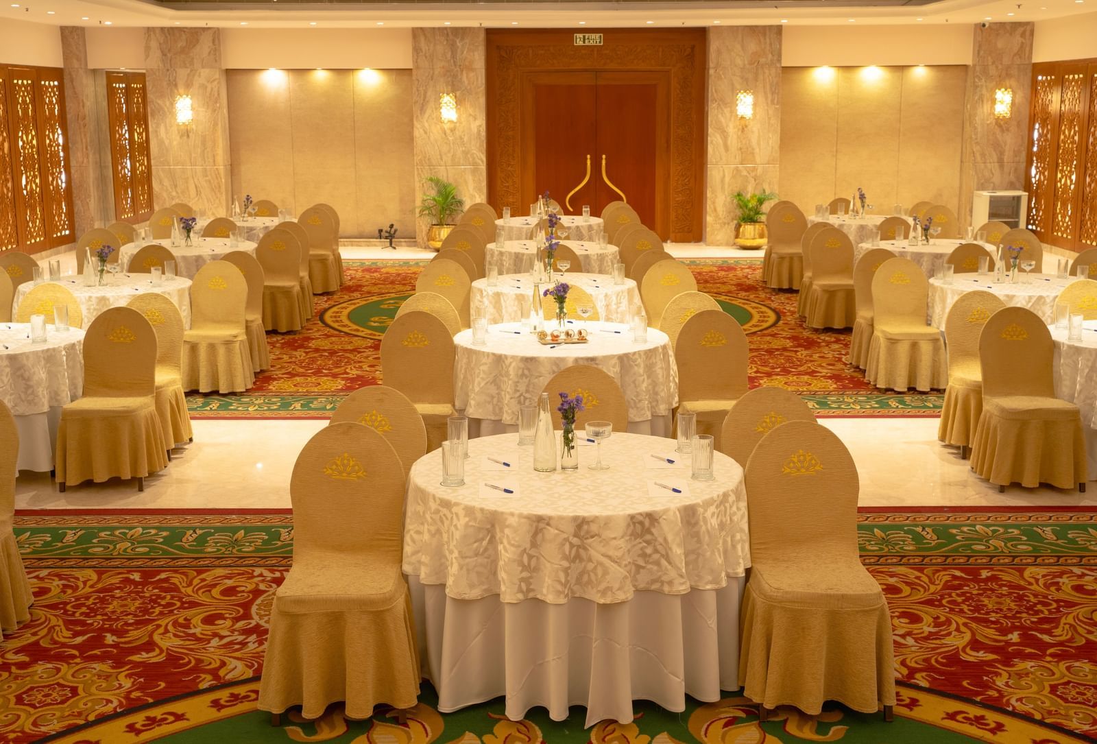 A banquet hall set up with round tables, elegant chairs, and warm lighting - Accord Puducherry