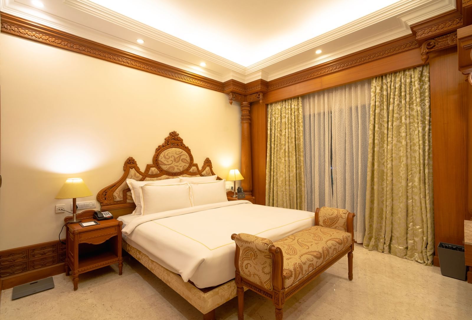 Hotel room with a king size bed, bedside tables, and curtains.
