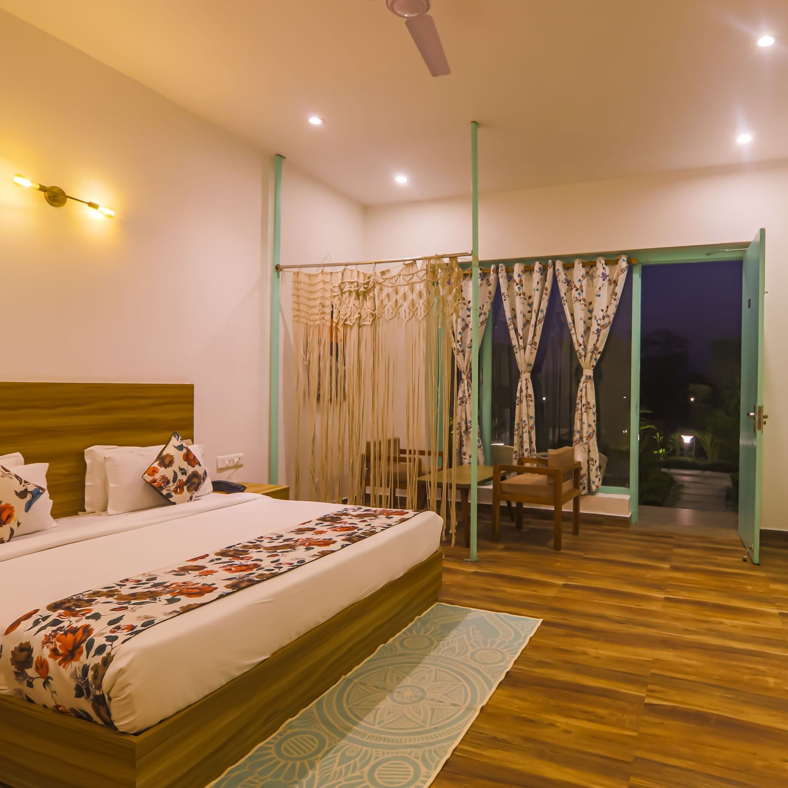 A well-lit bedroom at Vedikant Resorts The Mallard Corbett features a bed, seating area, and open balcony doors.