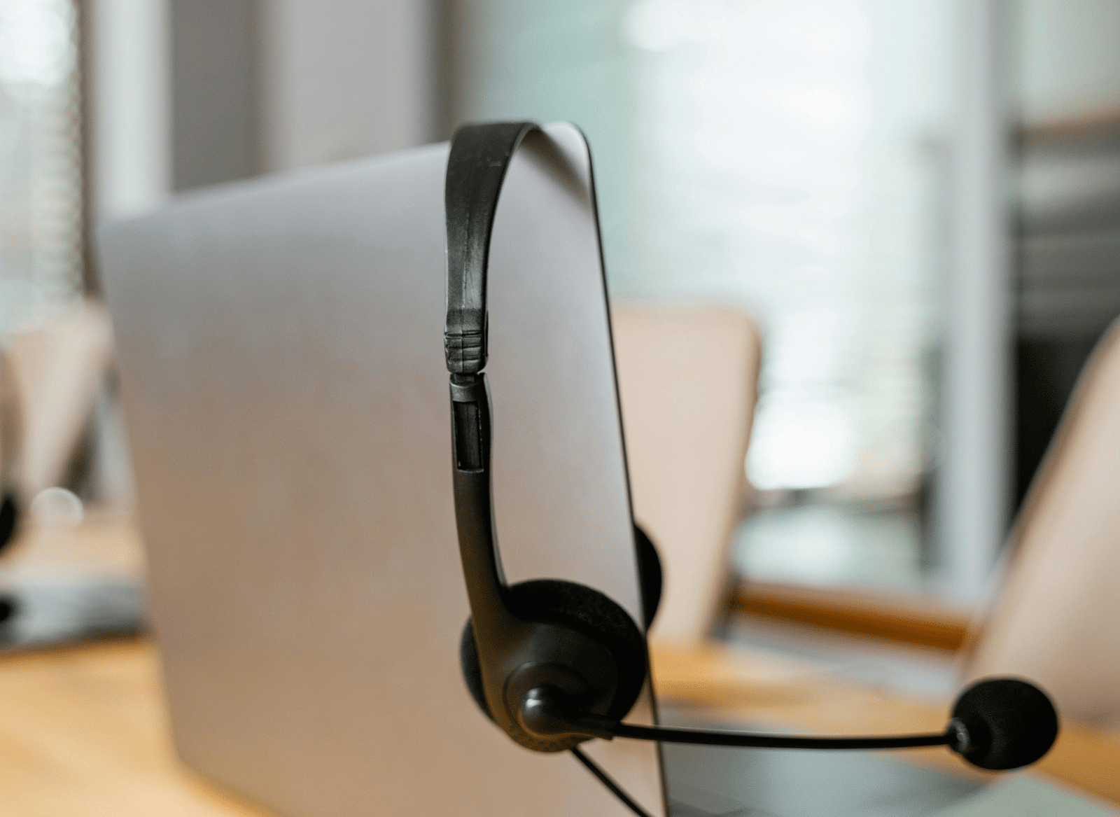 A headphone with a mic hung off a silver laptop screen.