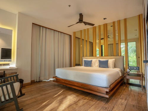 A contemporary bedroom at Azaya Beach Resort Goa featuring a floating wooden bed, timber wall panelling, and soft neutral tones.