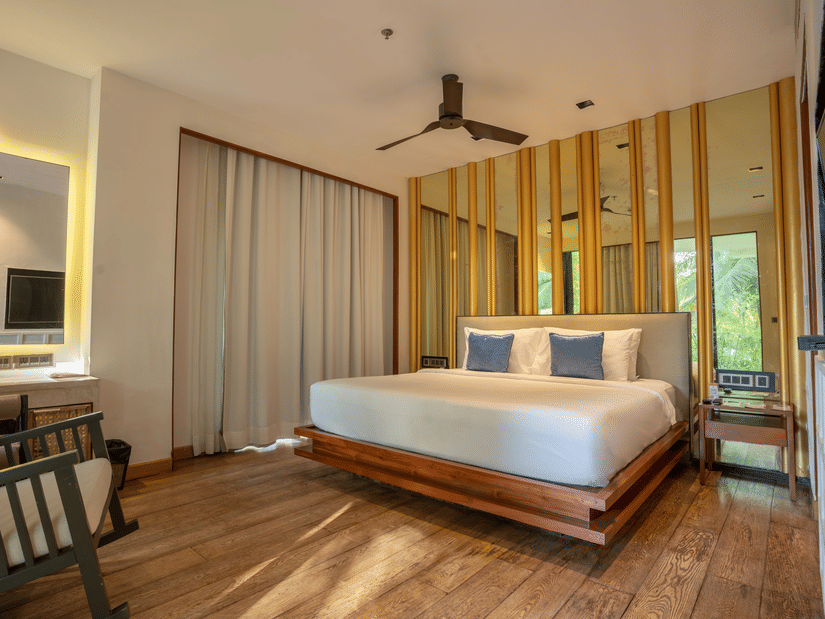 A contemporary bedroom at Azaya Beach Resort Goa featuring a floating wooden bed, timber wall panelling, and soft neutral tones.