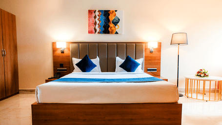 Junior Suite with a king bed, teal cushions, marble flooring, an armchair and a work desk with a table lamp at Ilara Hotels & Spa, Tada.