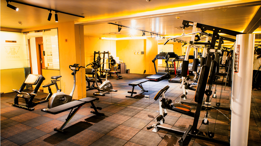 Cardio zone of the fitness centre with treadmills, cross trainers and leg press machines beside mirrored walls at Ilara Hotels & Spa, Tada.