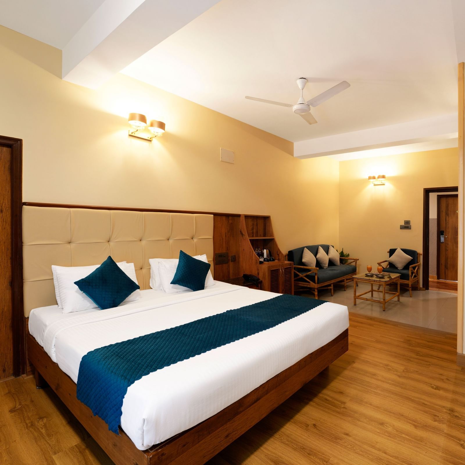 Executive Room with a queen size bed under warm lighting and the way to bathroom few steps away from it, a seating area in the background at Cross Roads Inn, Bengaluru