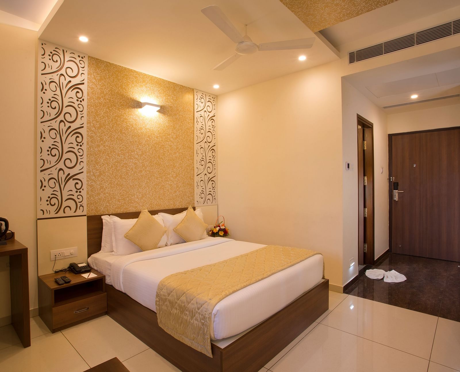 A hotel bedroom with a plush bed, decorative wallpaper and a view into the hallway - De Venetian by TGI, Brookefield