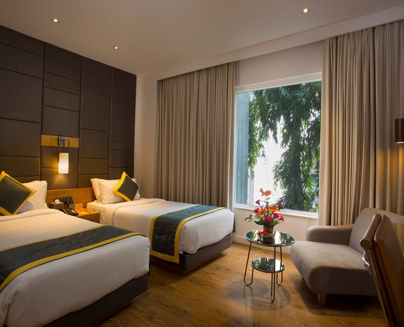 a bedroom with the curtains drawn out offering views of the city with two single beds and a sofa  - Hotel Fountain Tree By TGI - JP Nagar, Bangalore