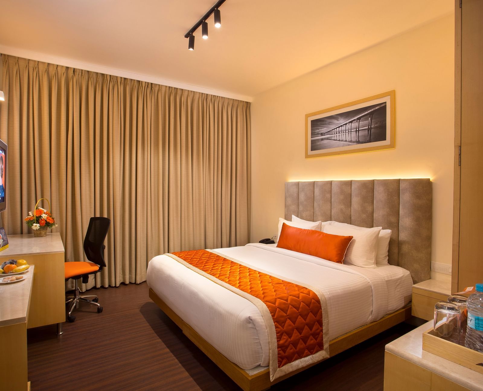 A cosy hotel room with a plush bed adorned with an orange bed runner, a work desk and a wall-mounted TV - Hotel Langford Keys by TGI, Shanti Nagar