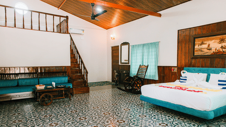 A large bedroom featuring multiple double beds with white linen, a wooden staircase, and wooden flooring | Vintage Trails By Ilara