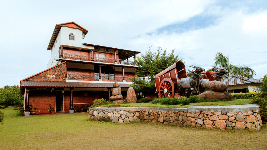 An exterior daytime view of a multi-storey wooden resort building with a green lawn in front | Vintage Trails By Ilara