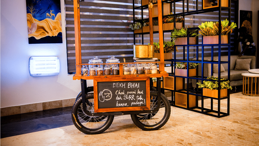 Wooden tea cart in the lobby with glass jars of ingredients, a brass pot and a playful Hindi chalkboard sign at Ilara Hotels & Spa, Tada.