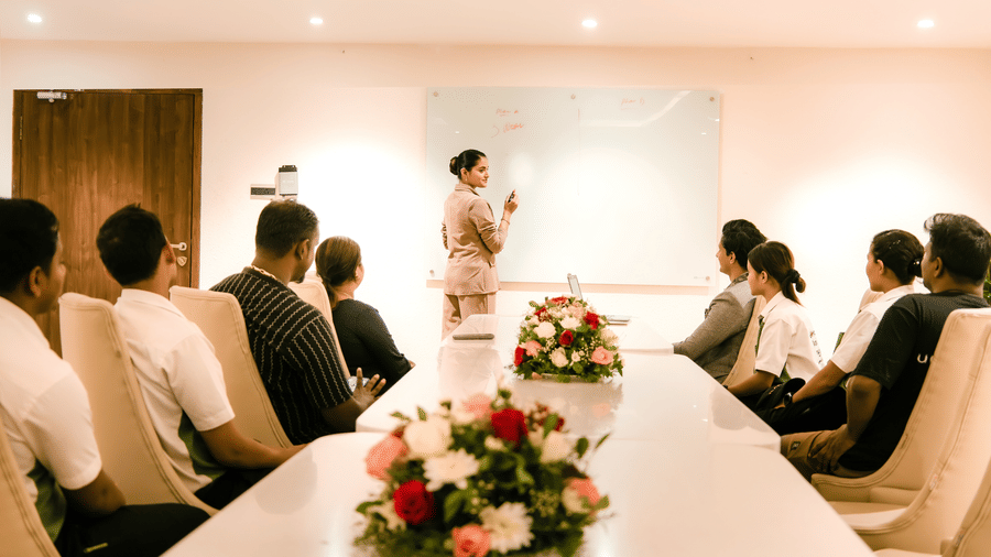 A warmly lit boardroom at Ilara Hotels & Spa, Tada, with several corporate delegates facing the projector screen during a meeting.