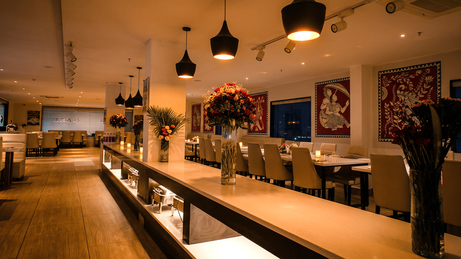 Evening view of the buffet counter with tall flower vases and candlelit tables at Tandoori Tamashaa restaurant, Ilara Hotels & Spa, Tada.