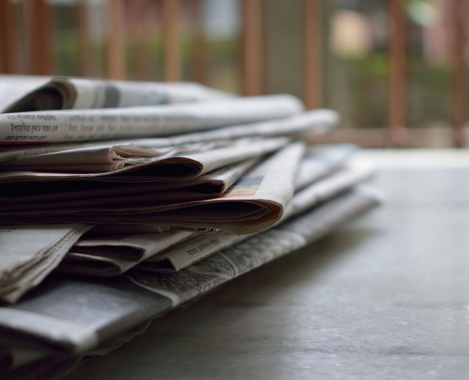 Newspaper stack placed on a wooden table.