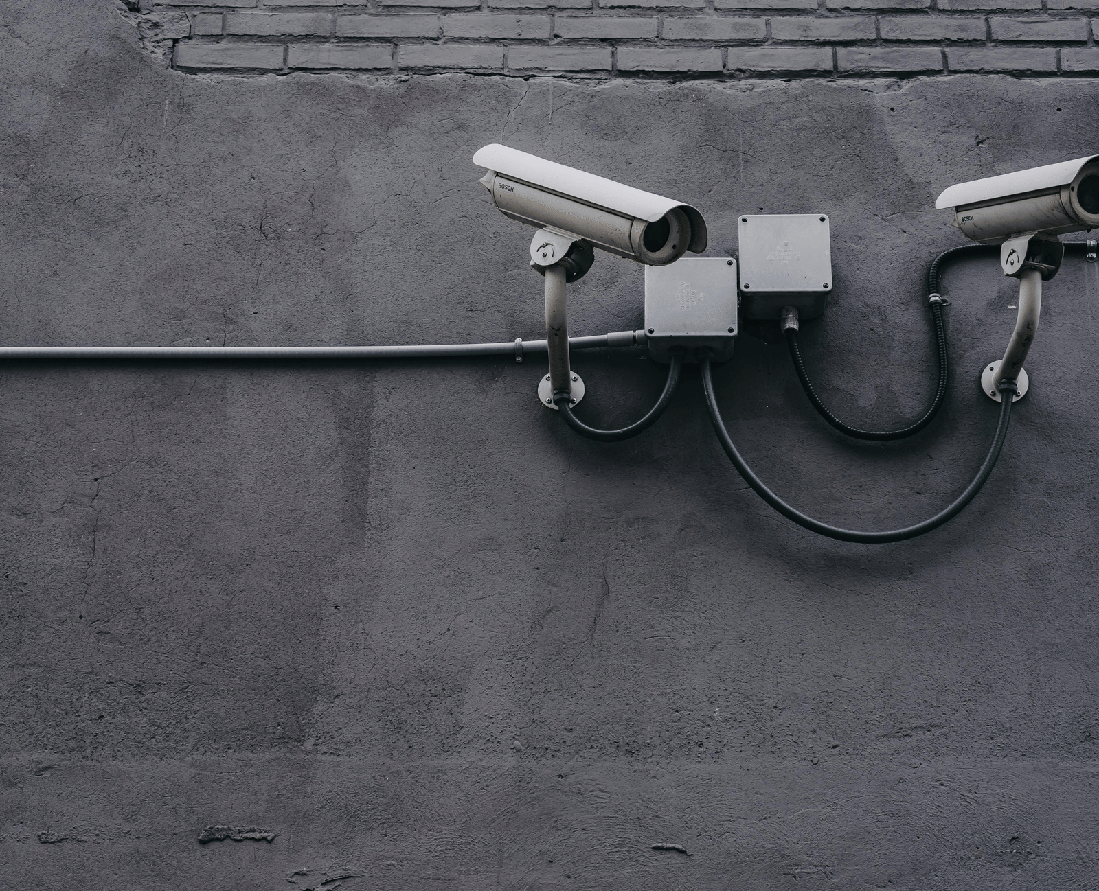 Wall-mounted CCTV cameras fixed on a grey exterior wall.