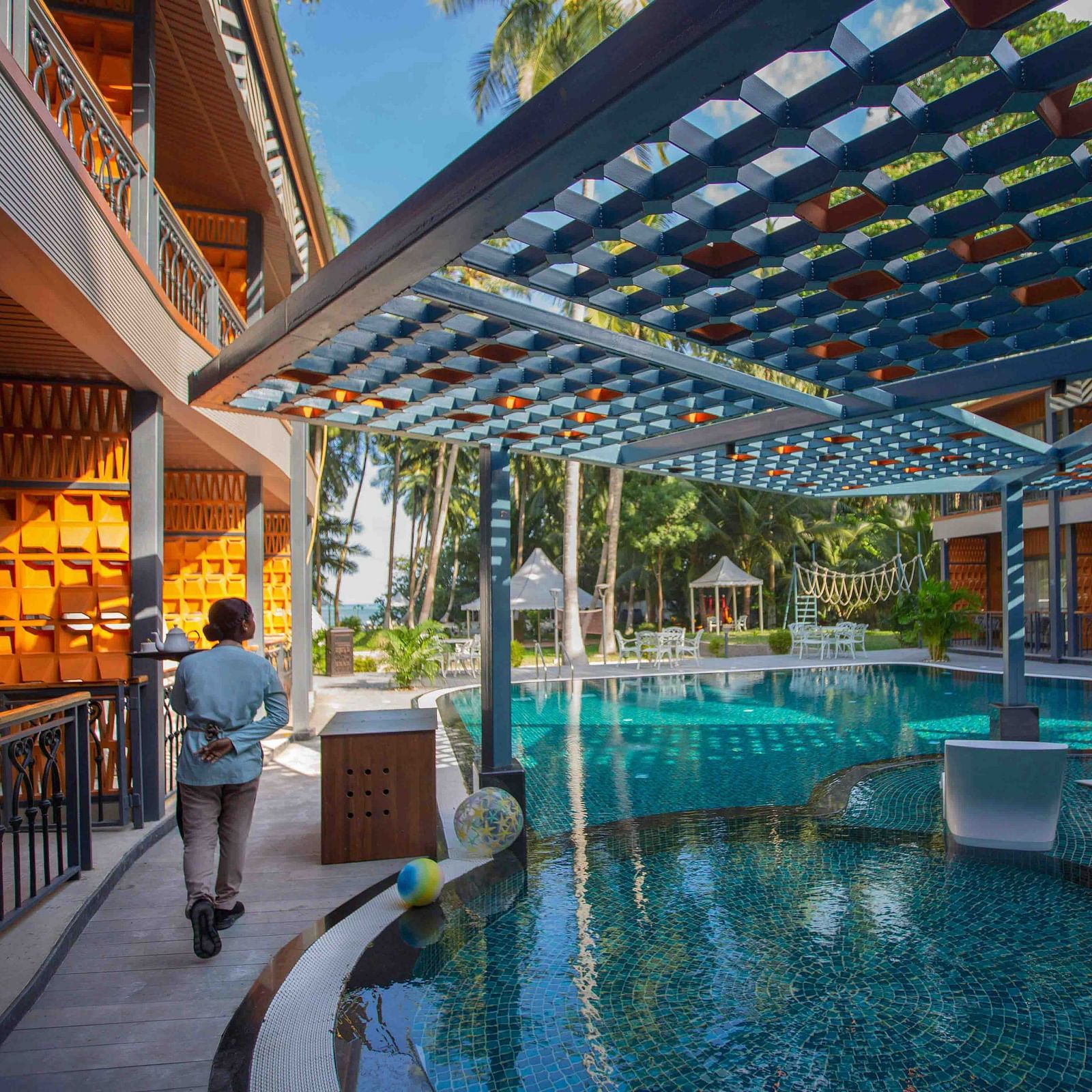 A woman walking around a designer pool with fancy roof, built in between two buildings.