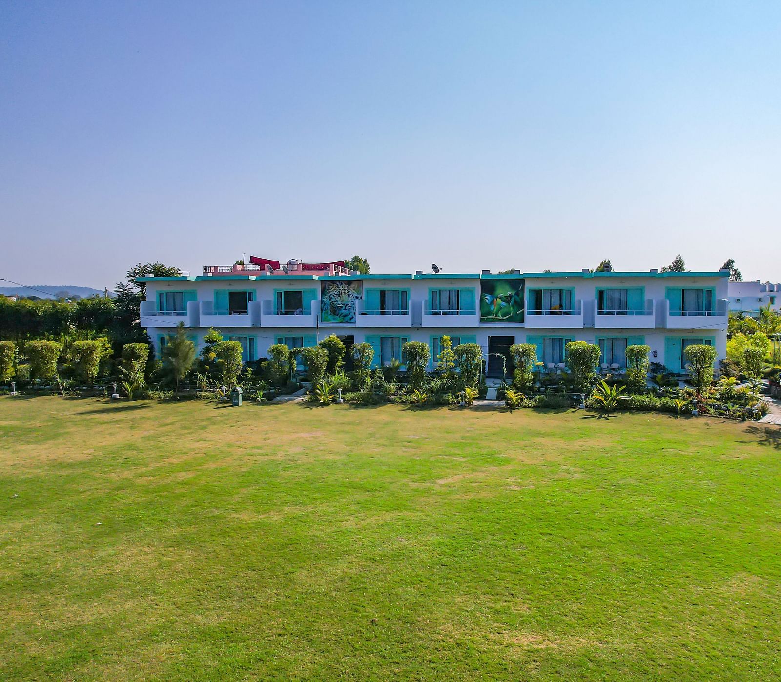Open lawn at Vedikant Resorts The Mallard Corbett with trimmed grass, resort buildings in the background, and no visible guests.
