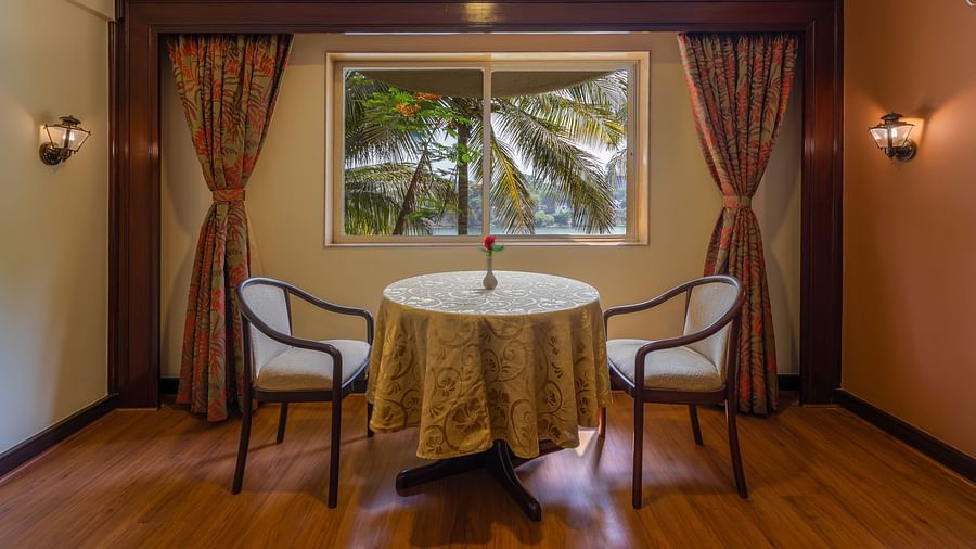 Two cosy chairs around a coffee table in a symmetrical layout, with a view greenery through a window – Ras Resort by Treat