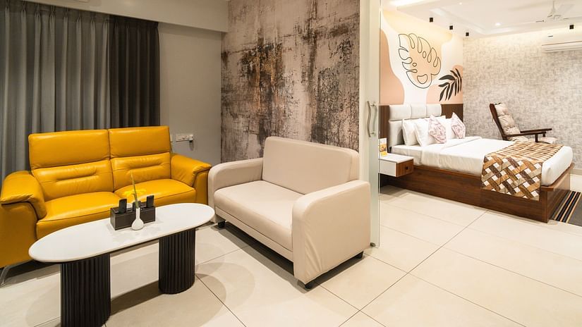 An image of a room with a plush bed in the bedroom and sofas placed around a coffee table in the living room - MGM Whispering Meadows