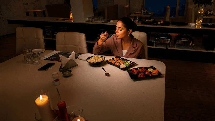 Guest tasting a spoonful at a candlelit table set with fried rice and tandoori platters at Tandoori Tamashaa, Ilara Hotels & Spa, Tada.