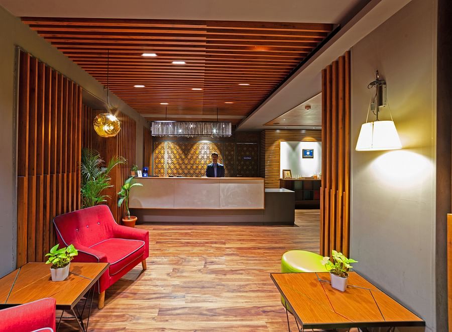 The welcoming lobby of Icon Boutique Hotel by Bhagini, Domlur, featuring a wooden ceiling, comfortable seating, and a reception desk.