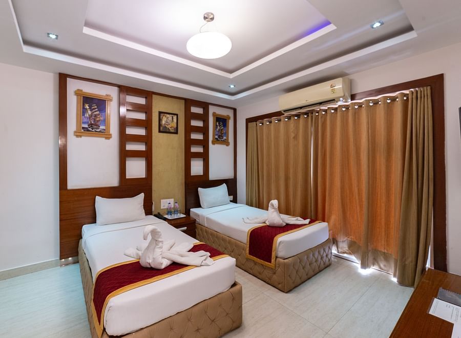 Comfort-focused twin bed setup with a muted golden curtain backdrop, warm lighting, and minimal clutter, providing a peaceful atmosphere for longer stays.