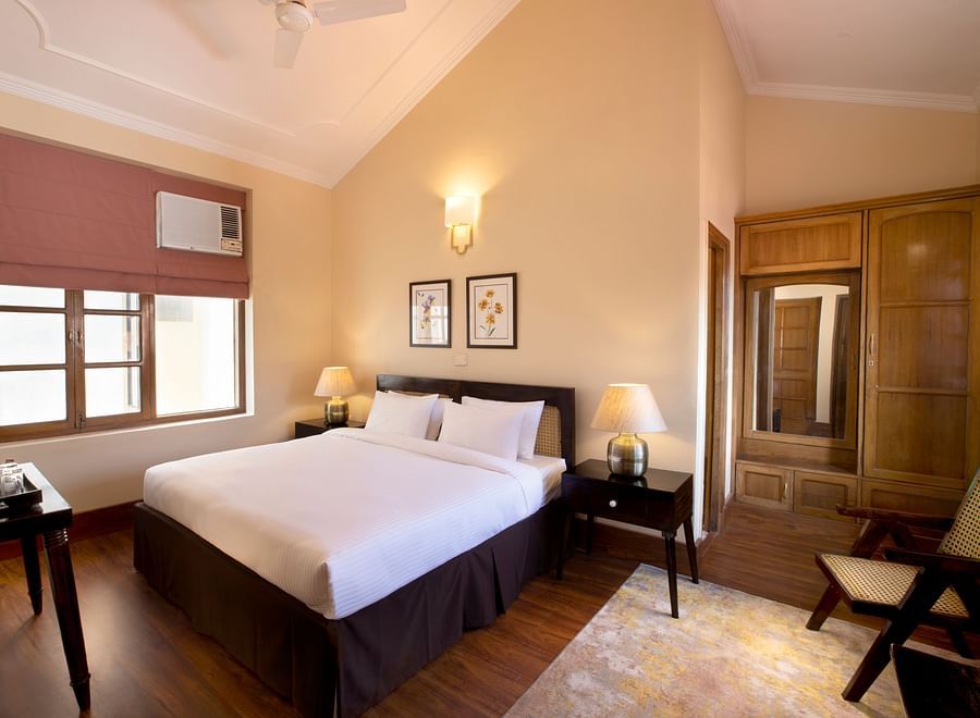 An image of a super Deluxe Room ,equipped with soft bedding, flat TV screen, a table with decorative items, and a chair - Lamrin Boutique Cottages Rishikesh