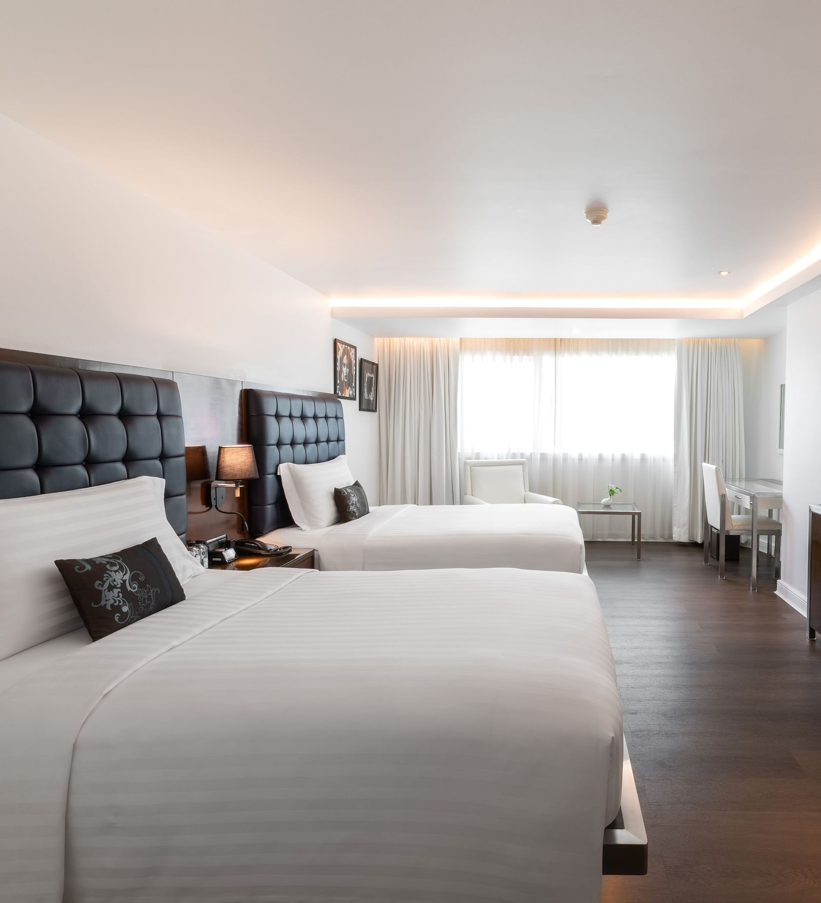 Two single beds with a lamp in the centre and a tv wall mounted opposite it - Night Hotel Bangkok.
