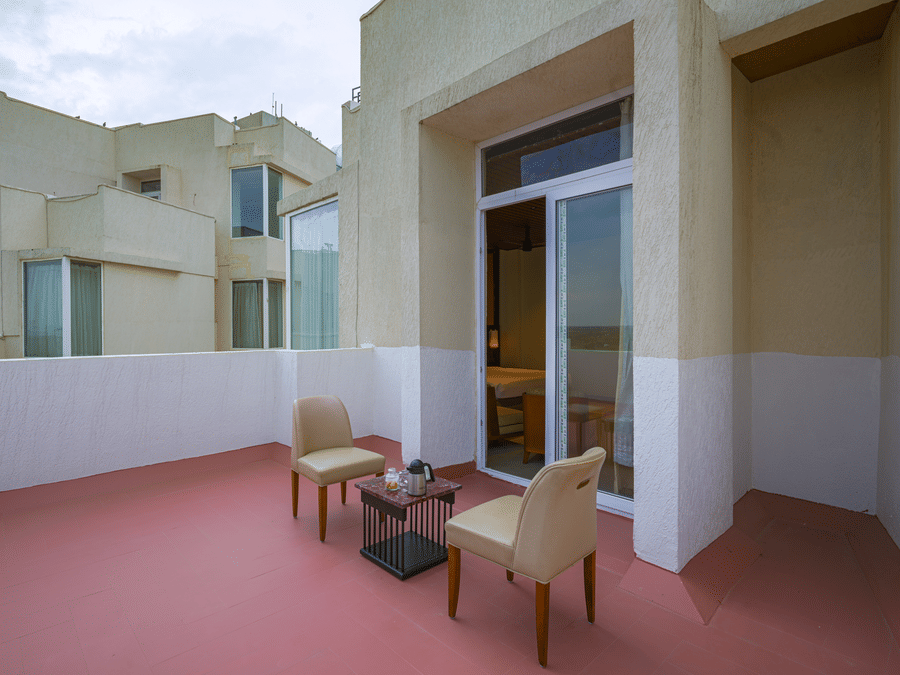 Private hotel terrace with outdoor chairs and a table overlooking the surrounding buildings.