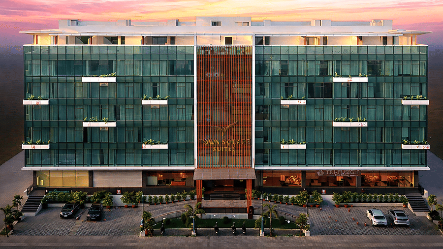 Exterior view of Town Square Suites at sunset showing modern glass facade and illuminated building.