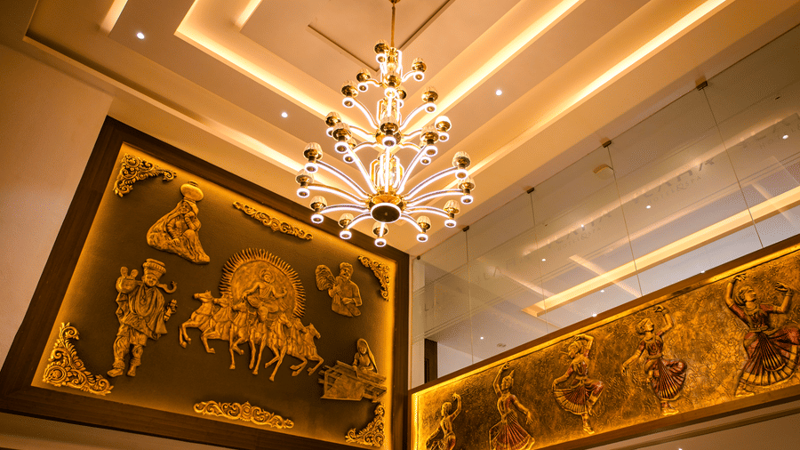 Gilded relief murals and a frieze of classical dancers beneath a chandelier on the cove-lit lobby ceiling at Ilara Hotels & Spa, Tada.