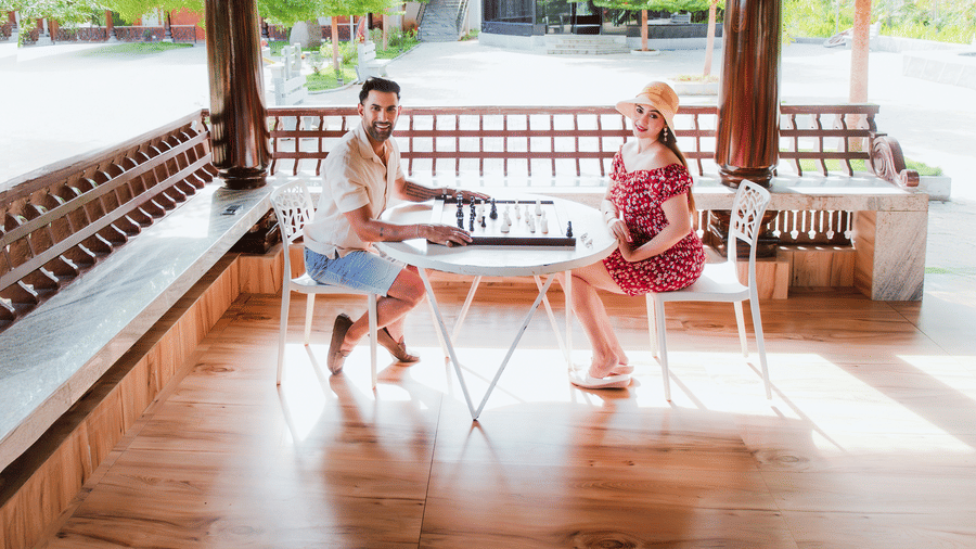 A man and a woman playing board games at a small table on a wooden-floored outdoor porch | Vintage Trails By Ilara
