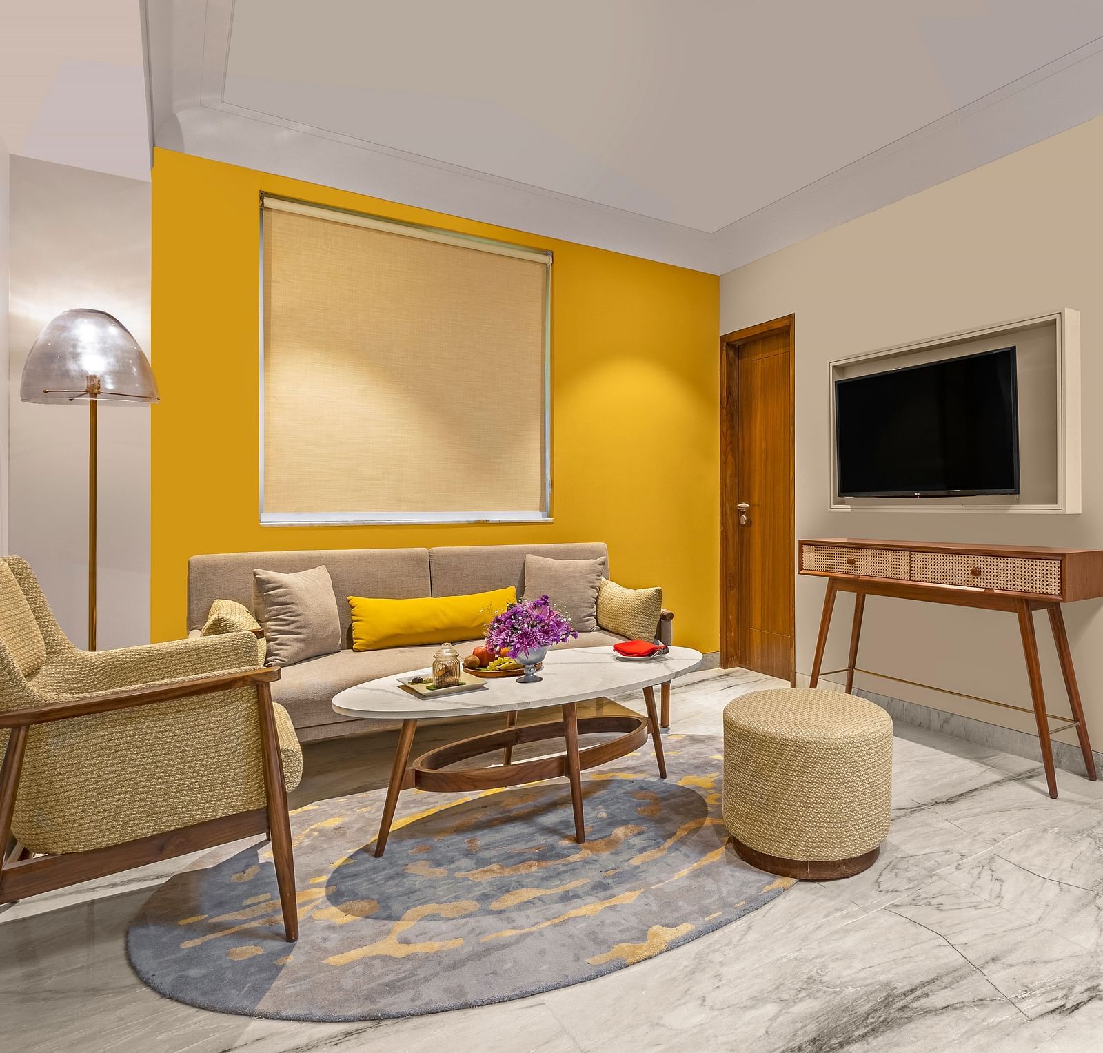 The room features a comfortable sofa with colourful pillows, a round coffee table, A floor lamp stands beside the sofa, providing ambient lighting.