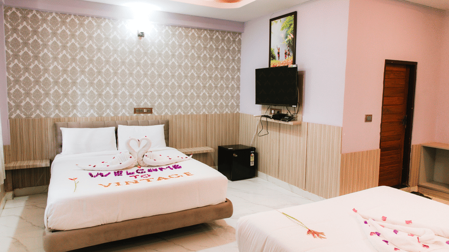 A bedroom containing two double beds, a wall-mounted TV, and patterned wallpaper | Vintage Trails By Ilara