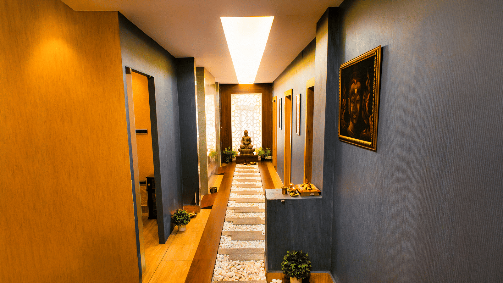 Spa corridor with a pebbled walkway, stepping stones, a Buddha statue before a lattice screen and a Buddha painting at Hasta Spa, Ilara Hotels & Spa, Tada.