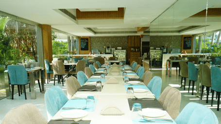 Long indoor dining table setup with turquoise chairs and neatly arranged tableware - Grande Bay Resort & Spa, Mamallapuram