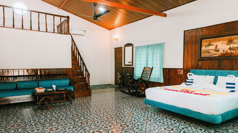 A large bedroom featuring multiple double beds with white linen, a wooden staircase, and wooden flooring | Vintage Trails By Ilara