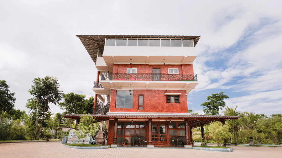 A front exterior view of a tall multi-level building featuring brick accents and outdoor balconies | Vintage Trails By Ilara