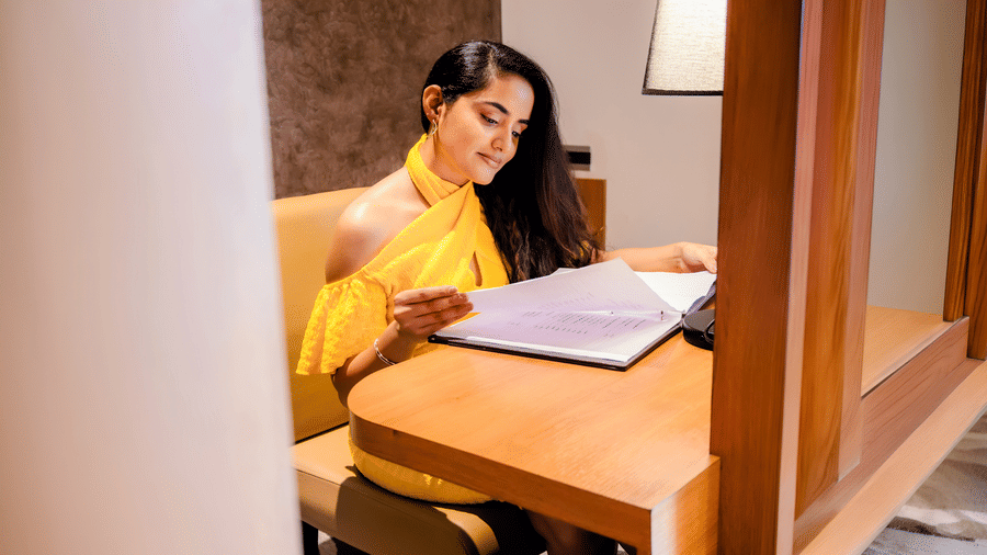 Guest reading at the wooden writing desk of the Executive Suite, with a shaded table lamp and a textured accent wall at Ilara Hotels & Spa, Tada.