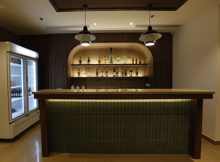 An image of bar counter displaying various liquor bottles placed on shelves and refrigerator at Tulip Inn, Zirakpur
