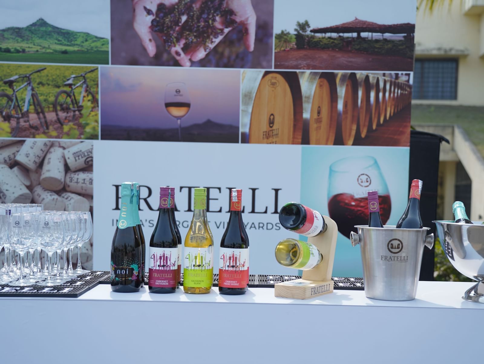 A display table outdoors features various bottles, glasses, and decorative elements, likely for a beverage tasting or event | Vedic Village Spa Resort, Kolkata