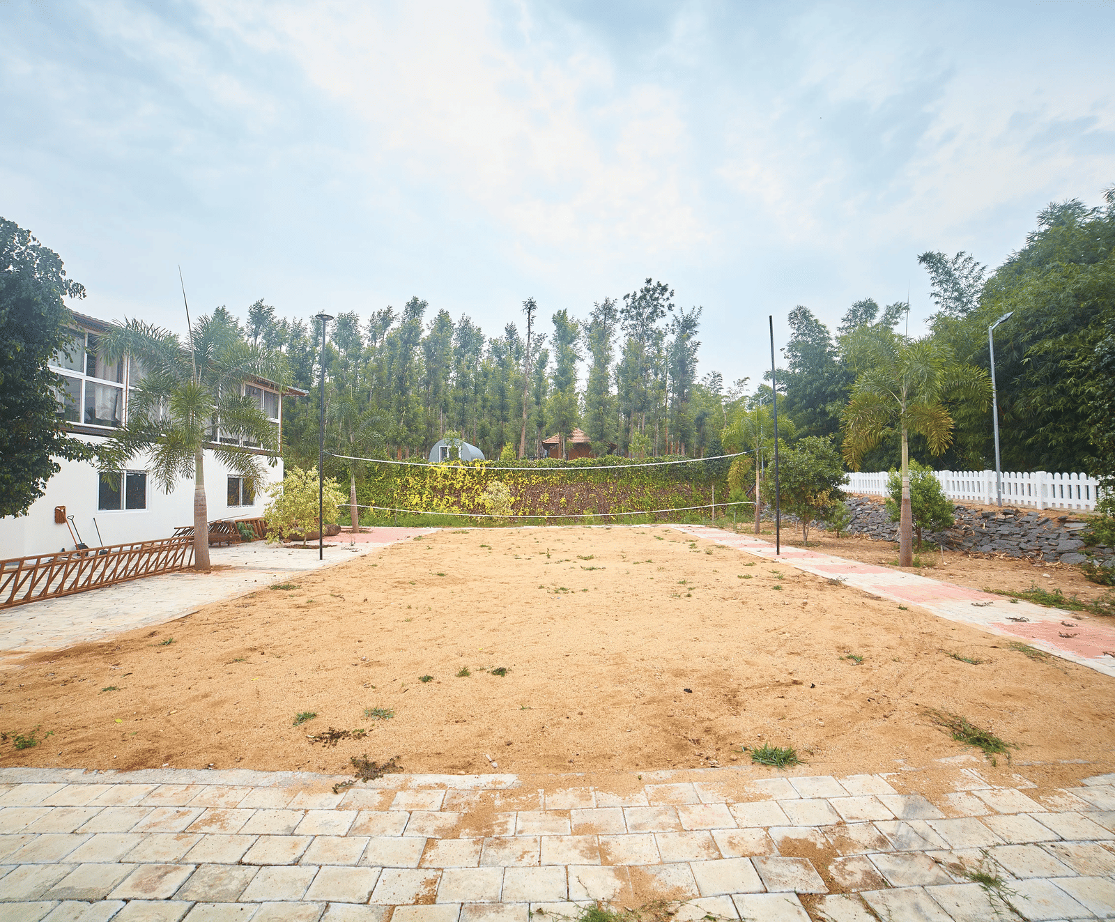 A wide, open expanse of dry, light brown ground, possibly a sports field or open space, with buildings and trees in the background under a pale sky - Vintage Trails By Ilara