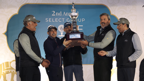 Couple of people standing on a stage holding a trophy.- Heritage Village Resorts & Spa